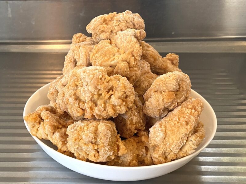 業務スーパー「お肉にこだわった美味しい唐揚げ（タイ産）」1kgを皿に山盛りにした写真。調理前の冷凍状態。