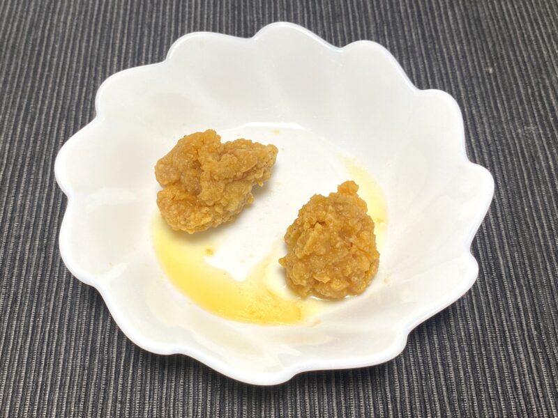 業務スーパー「お肉にこだわった美味しい唐揚げ（タイ産）」を電子レンジで加熱した状態。皿にはレンジ調理で出た油が残っている。