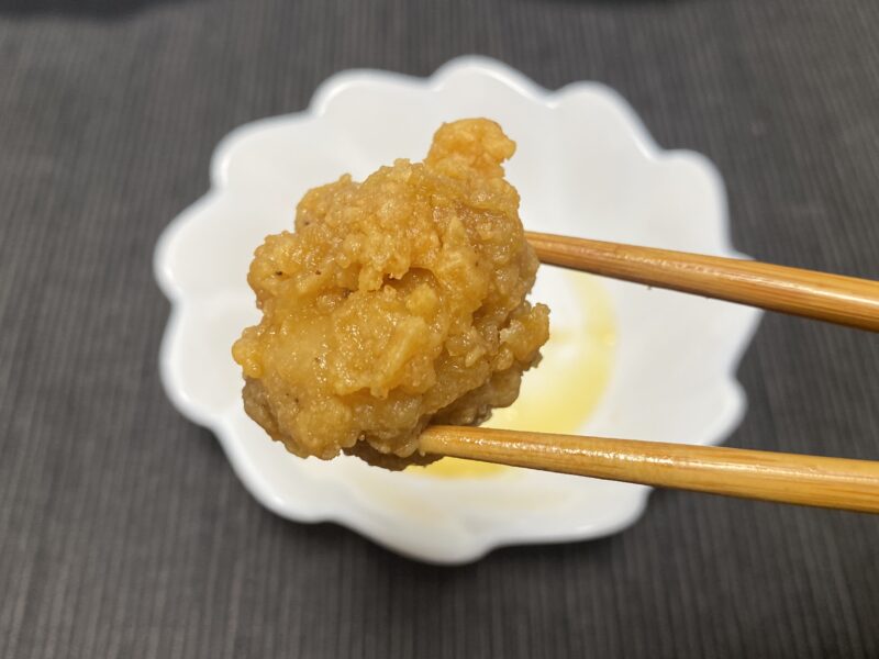 電子レンジで加熱した業務スーパー「お肉にこだわった美味しい唐揚げ（タイ産）」を箸で持ち上げた試食シーン。