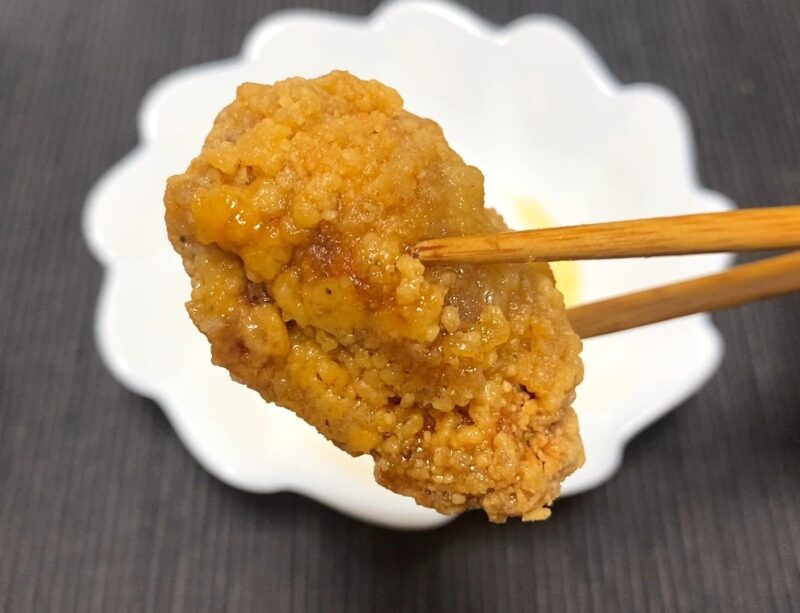 電子レンジ加熱で衣がしっとりした唐揚げを箸で持ち上げた写真。衣の油分がにじみ、食感が柔らかくなっているのが見える。