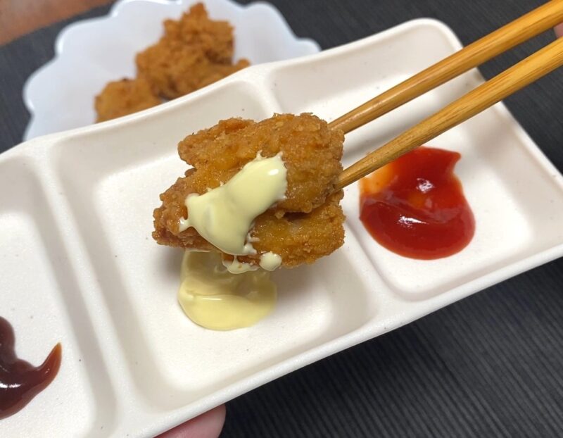 マヨネーズを付けた唐揚げを箸で持ち上げたアップ写真。衣がしっとりしており、マヨがとろけている様子が分かる。