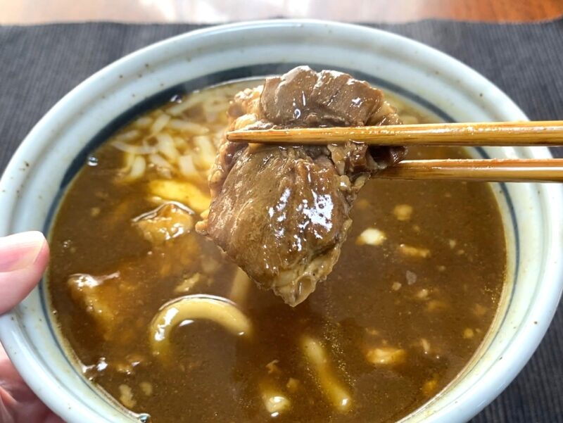完成した角煮カレーうどん 箸で持ち上げた麺と角煮