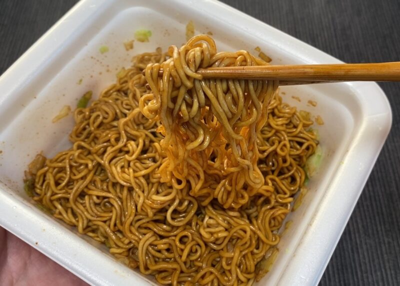 ソースをしっかり混ぜ合わせた完成図。細めの麺に濃厚なソースが絡み、箸で持ち上げられた様子。