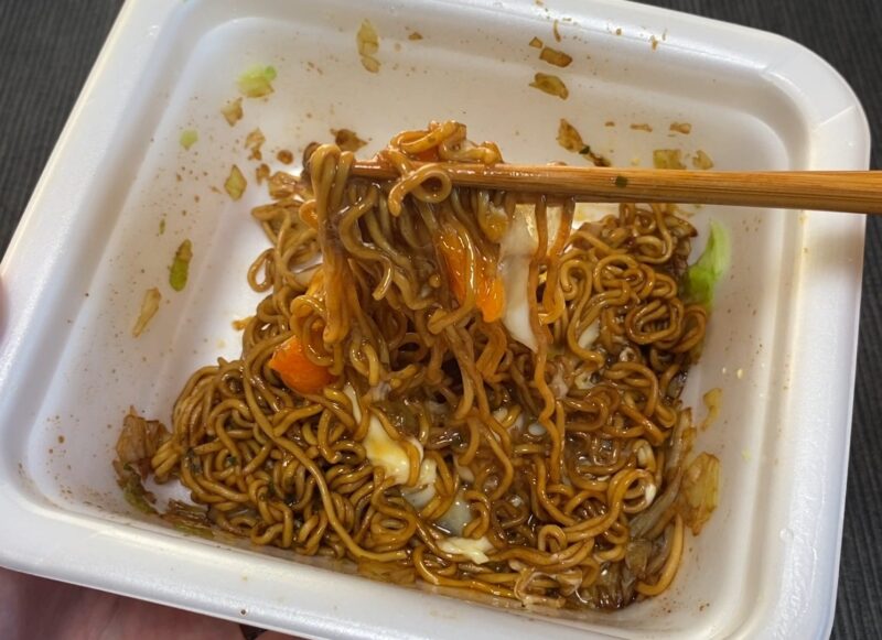 焼きそばに半熟卵をトッピングし、とろりとした黄身が麺に絡みついている実食カット。