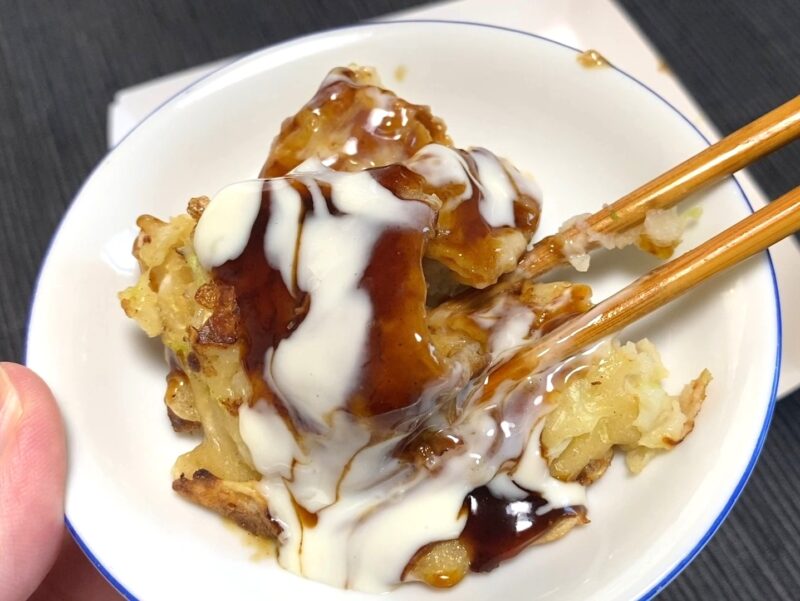 マヨネーズ風ソースをかけたお好み焼きを食べる