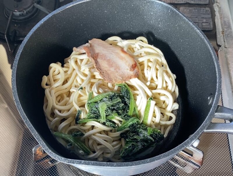 鍋で加熱中の冷凍ラーメン 水を使わずそのまま温める様子
