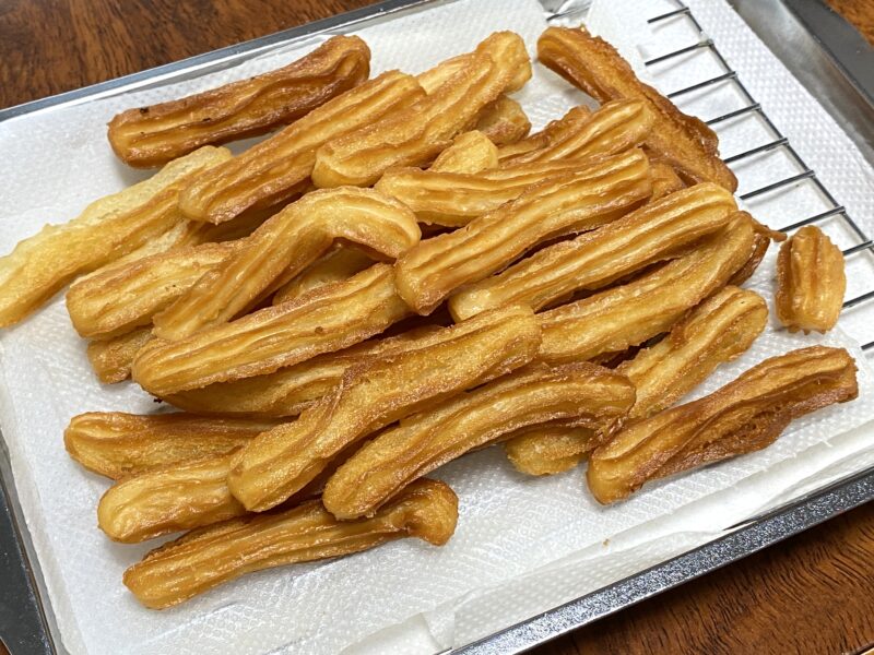 皿に山盛りにされた揚げたてのチュロス 黄金色の仕上がり