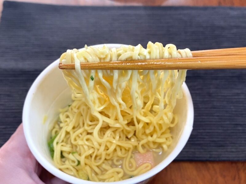 コスモスON365・シーフードヌードルの専用麺を箸で持ち上げた様子・スープとよく絡んだ細麺