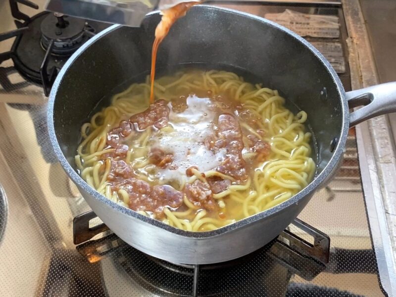 茹でた麺の入った鍋にスープを投入する調理工程