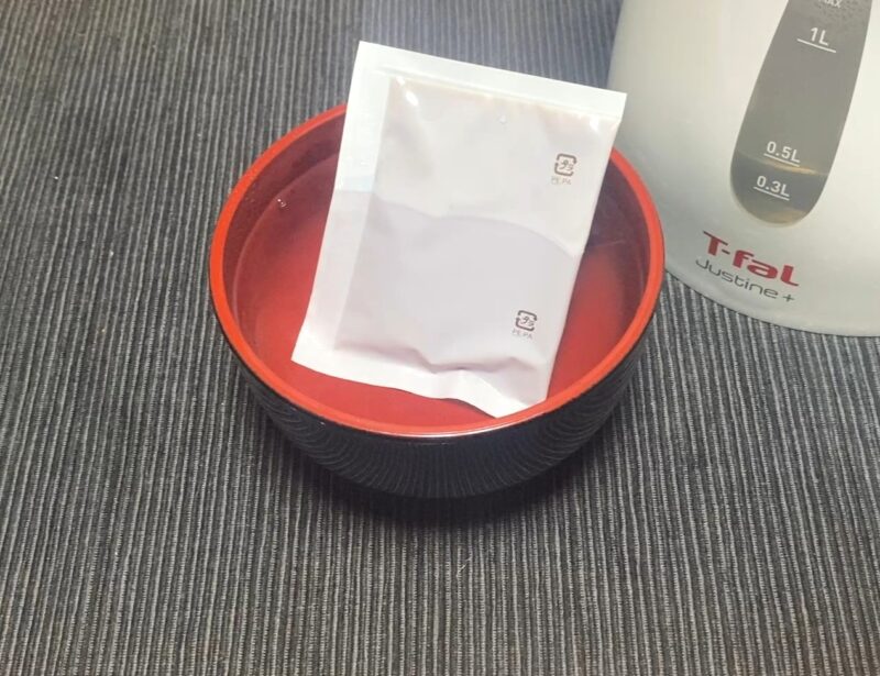 液体スープ袋をお湯で湯煎解凍し、カップの熱湯で溶かす様子