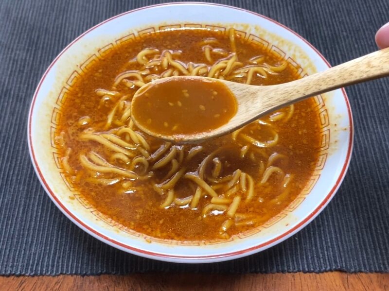山岡家乾麺・辛味噌の赤いスープをレンゲですくった様子