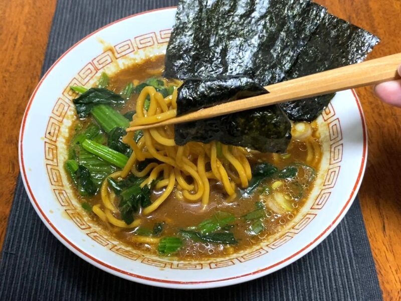 山岡家乾麺・味噌に海苔・ほうれん草・ネギをトッピングして箸で海苔を持ち上げた様子