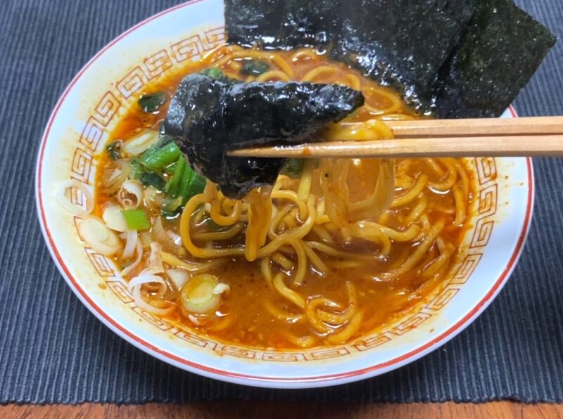 山岡家乾麺・辛味噌に海苔・ほうれん草・ネギをトッピングして箸で持ち上げた様子