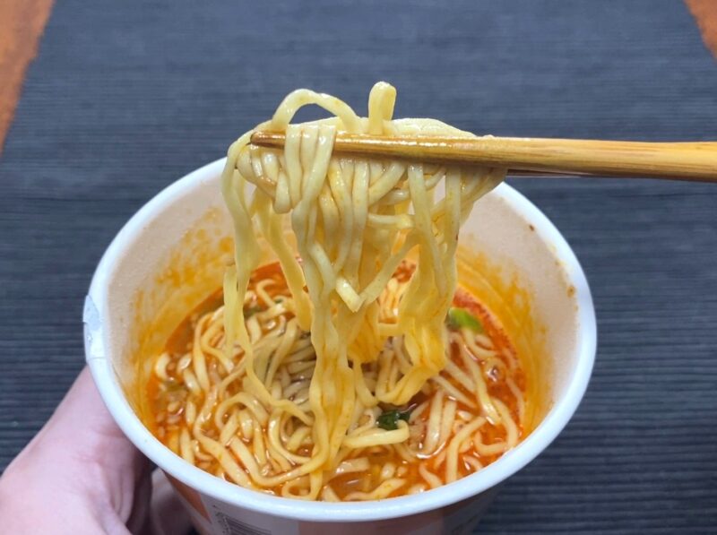 コスモスON365・担担麺の麺を箸で持ち上げた様子・赤いスープが絡んだ状態