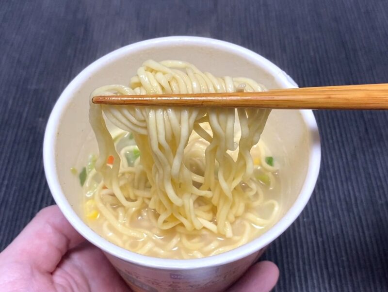 箸で持ち上げた野菜ちゃんぽんの麺。ちゃんぽんスープをまとったカップ麺の麺のアップ