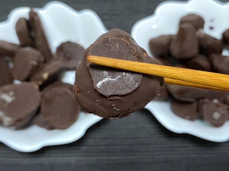 業務スーパー・チョコバナナ冷凍状態を箸で持ち上げたアップ・チョコが欠けたいびつな仕上がり