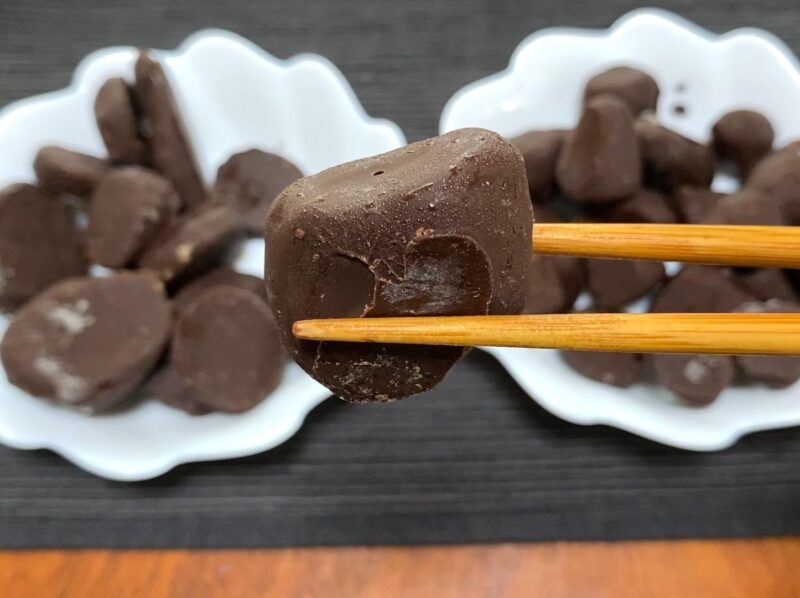 業務スーパー・チョコいちご冷凍状態を箸で持ち上げたアップ・パリッとしたチョココーティングの様子
