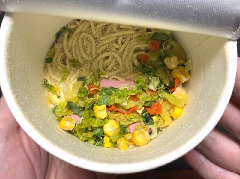 フタを開けた野菜ちゃんぽんの中身。キャベツ・コーン・人参・かまぼこ・ねぎの具材と麺が見える
