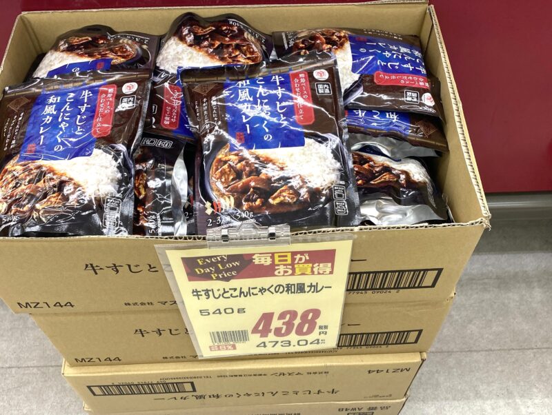 業務スーパーの店頭で段ボール山積みになった牛すじとこんにゃくの和風カレー・税込473円の値札付き