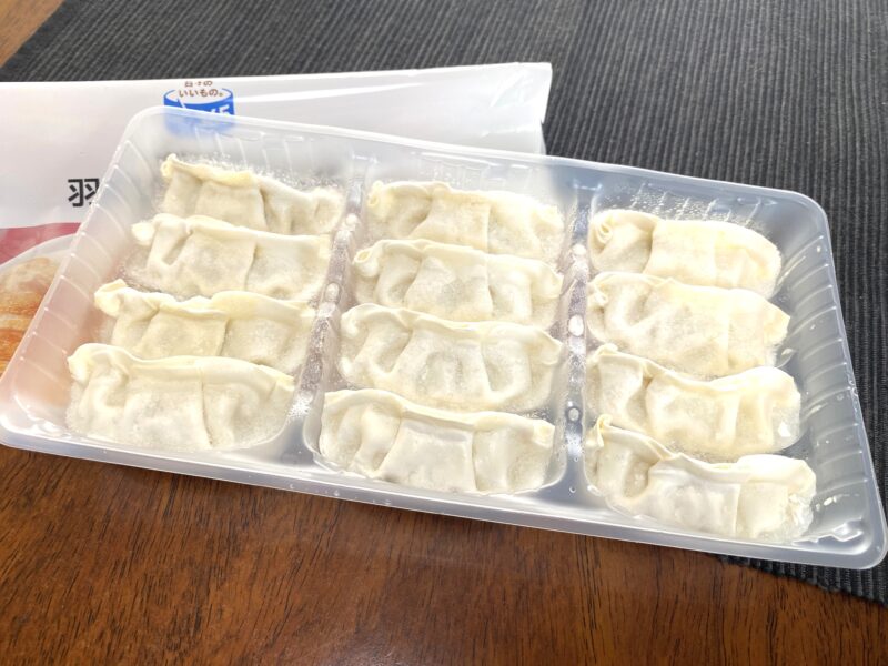 コスモス羽根つきギョーザをトレーから開封した状態。12個の冷凍餃子がトレーに整列している