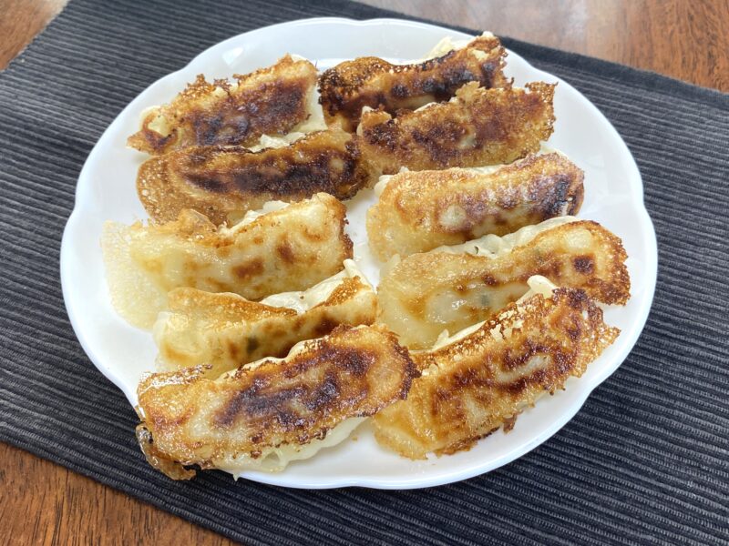 コスモス羽根つきギョーザを白い皿に盛り付けた焼き上がり。羽根がパリッと焼けた状態