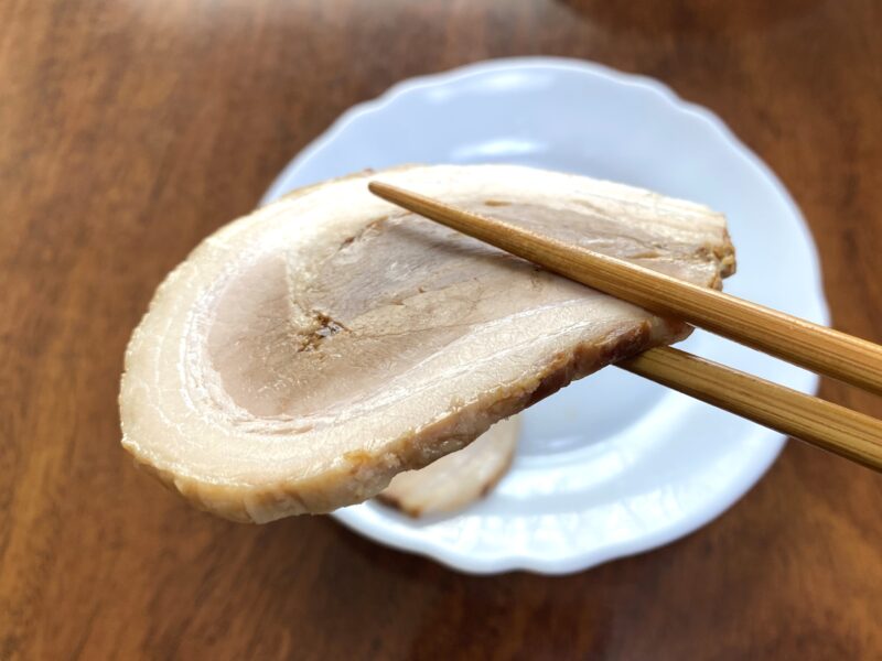 厚切りバラ焼豚を箸でつかんでいる様子