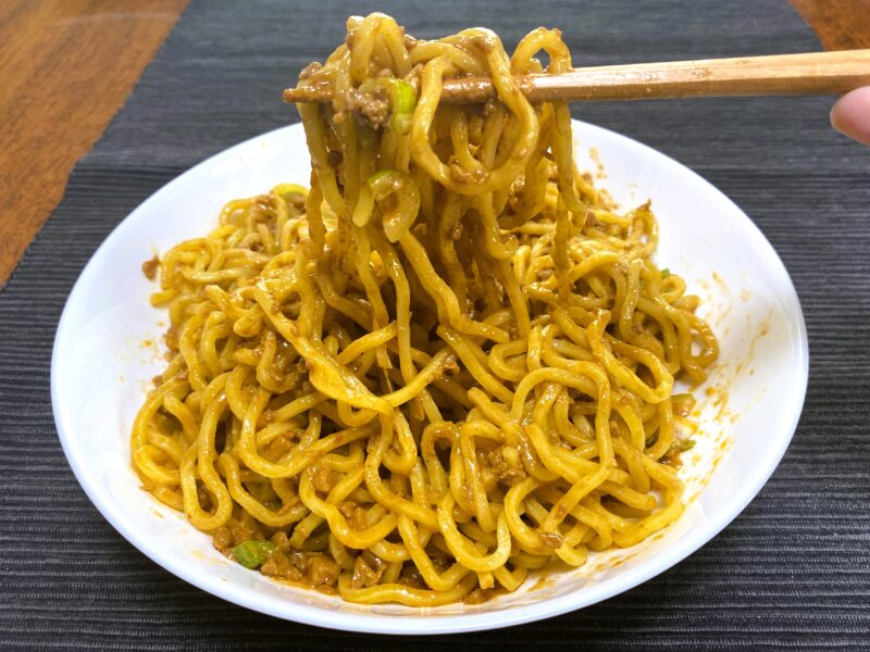 業務スーパー・汁なし担担麺の素の汁なし担担麵を箸で持ち上げた様子・ねっとりタレが絡んだワシワシ感