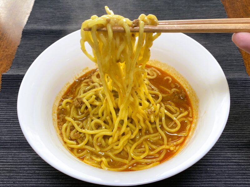 業務スーパー・汁なし担担麺の素のスープ担々麺を箸で持ち上げた様子・ズルズル食べられるスープが絡んだ麺