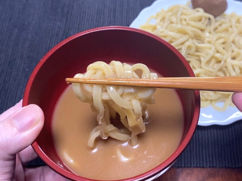 太麺を濃厚な豚骨魚介スープにくぐらせる実食シーン