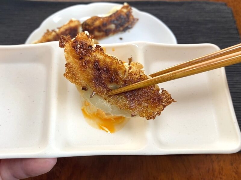 スモス羽根つきギョーザをマヨネーズとラー油のタレにつけている様子。羽根のパリパリ感が見える