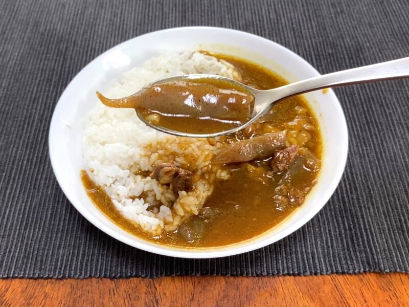 業務スーパー・牛すじとこんにゃくの和風カレーのこんにゃくをスプーンで持ち上げた様子・大きくカットされたこんにゃく