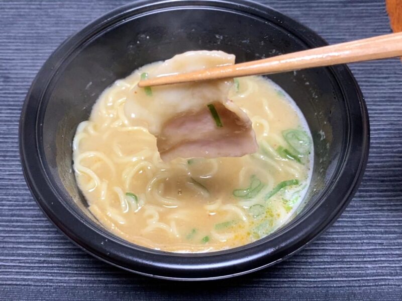 箸で天下一品監修ラーメンの煮豚を持ち上げたアップ。とろみスープに浸かった具材の様子