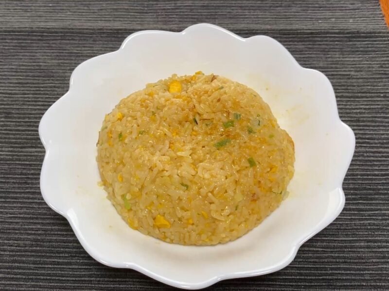 白い器に盛り付けた天下一品監修炒飯の全体。こってりスープが染み込んだしっとりとした見た目