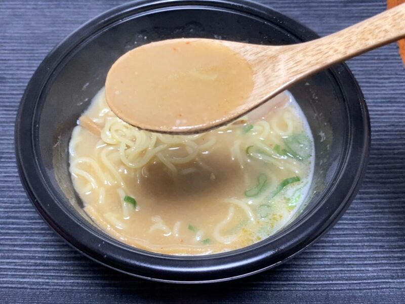 木製レンゲで天下一品監修ラーメンのスープをすくったアップ。とろ〜りまろやかな白濁スープの質感