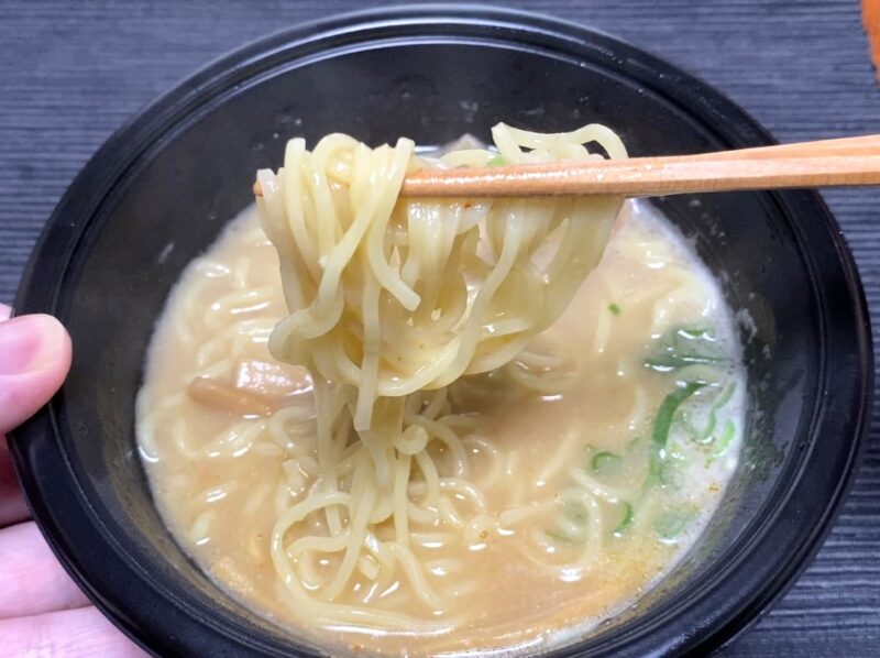 箸で天下一品監修ラーメンの麺を持ち上げたアップ。柔らかめの麺にとろみスープが絡んでいる"