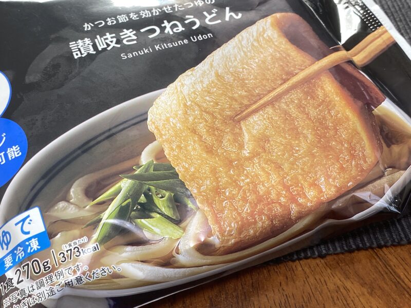 "讃岐きつねうどんのパッケージ正面アップ。大判おあげを箸で持ち上げた調理例写真