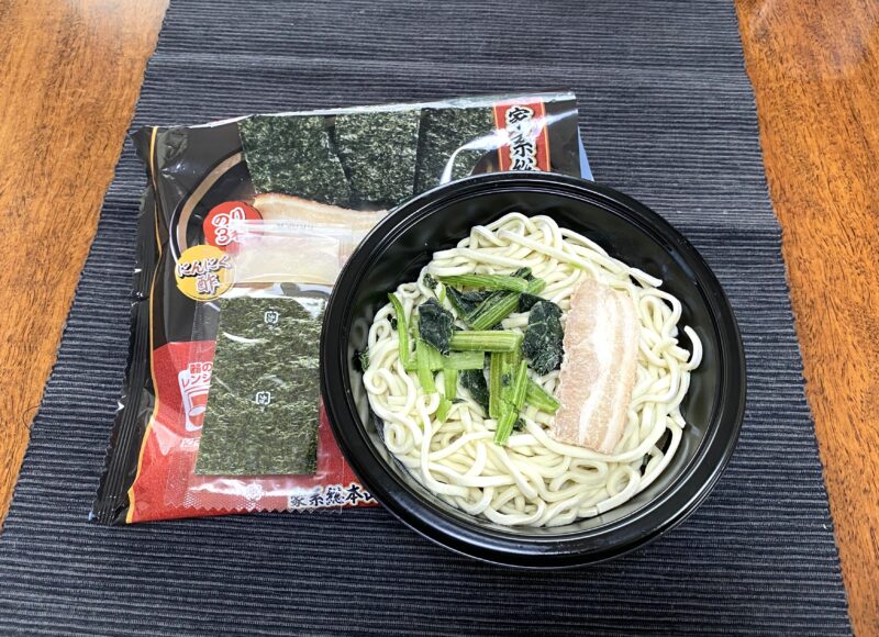 吉村家冷凍ラーメンを電子レンジ調理後の状態。黒い器に中太麺・ほうれん草・焼豚が入り、別添えの海苔・にんにく酢小袋とともに並べた様子