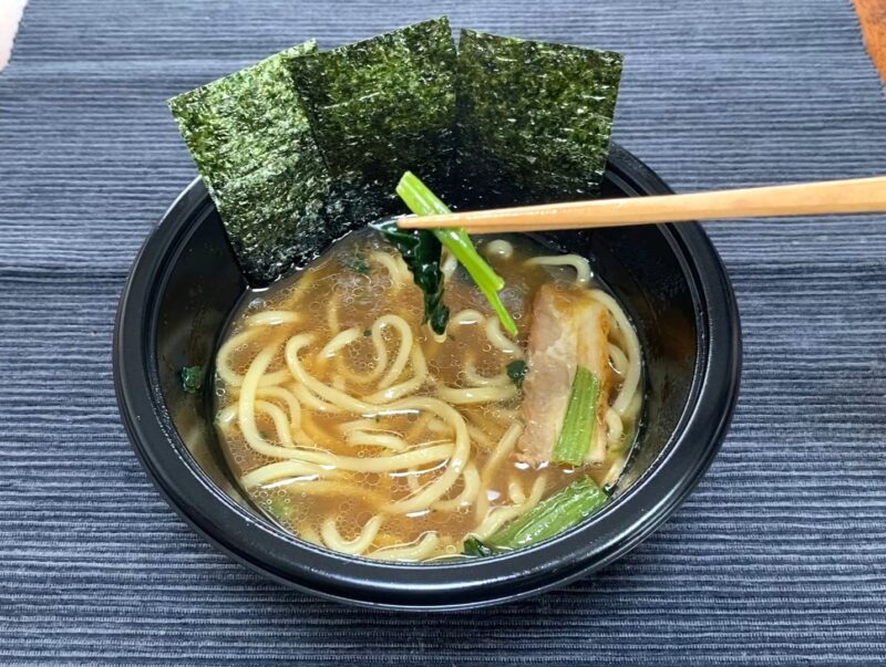箸でほうれん草をつまんだ様子。吉村家ラーメンの具材の茎が多いほうれん草のアップ