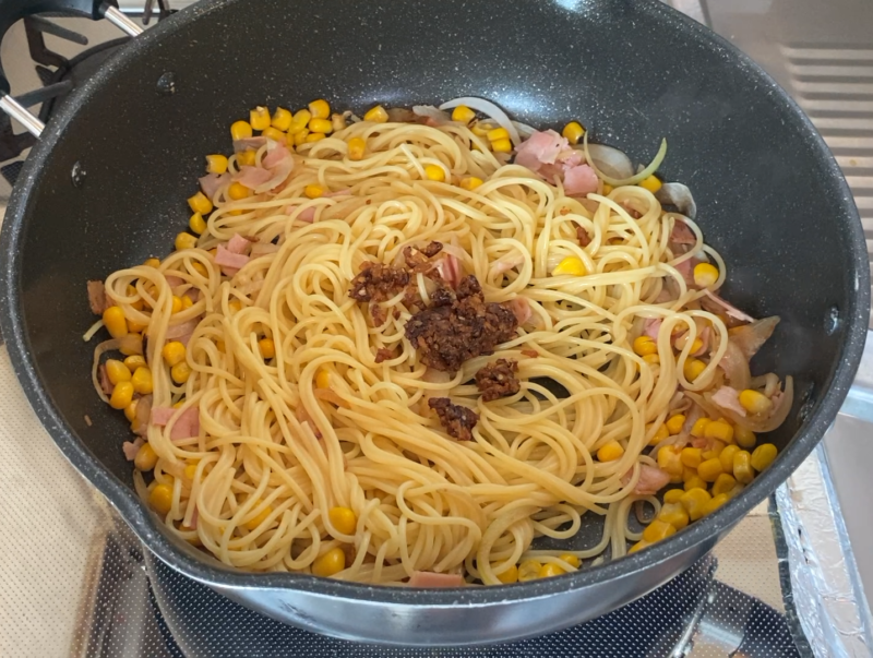 フライパンでベーコンとコーンを炒めたパスタに、ガーリックライスの素を加えたところ