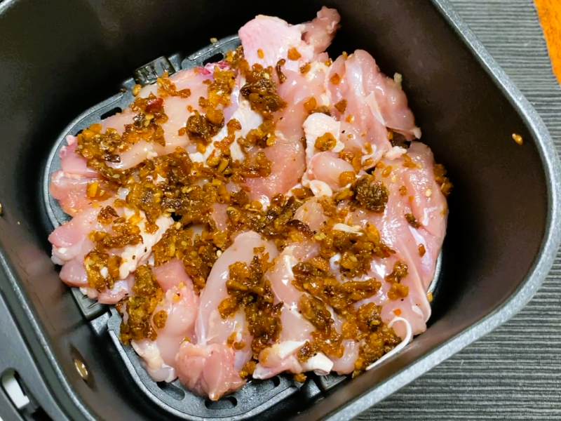 ノンフライヤーのバスケットに並べた鶏もも肉。ガーリックライスの素がまぶしてある